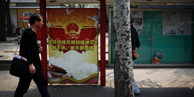 A man walks by a propaganda poster of China's Communist Party in Beijing. Photo / AP