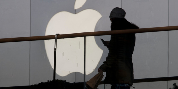 A woman using a phone walks past Apple's logo near its retail outlet in Beijing. The US Government now has to weigh whether to disclose security flaws to Apple. Photo / AP