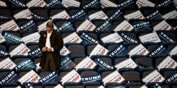 A man is surrounded by campaign signs before a rally for Republican presidential candidate Donald Trump in Albany, New York. Photo / AP