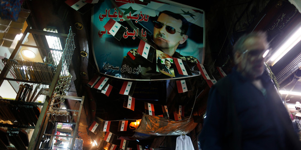 A Syrian walks under a poster of the Syrian President Bashar Assad at the popular Hamidiyeh old market in Damascus. Photo / AP