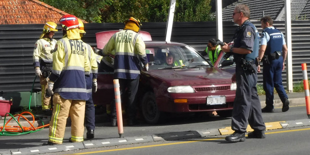 Firefighters cut free the male driver of a car struck by a fleeing driver. Photo / Kristin Edge