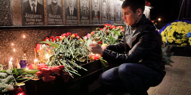 A man lights a candle to commemorate victims of the Chernobyl nuclear disaster, during a ceremony at the memorial to Chernobyl workers and firefighters in Slavutych, Ukraine. Photo / AP
