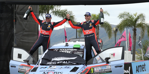 Hyundai Motorsports driver Hayden Paddon, right, and co-driver John Kennard, both from New Zealand, celebrate in the podium. Photo / AP.