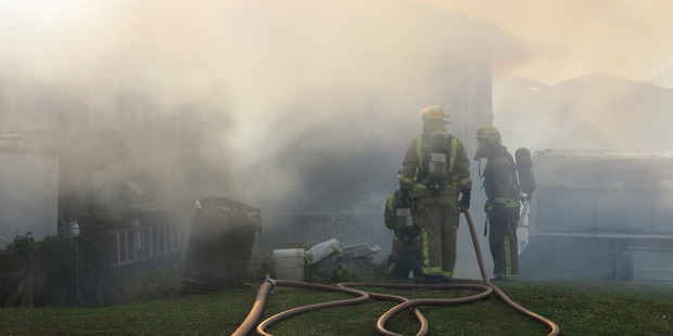 Firefighters work to put out a fire at a house in Te Puke. Photo/Pauline Carney