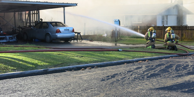 Firefighters work to put out a fire at a house in Te Puke. Photo/Pauline Carney