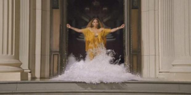 Beyonce emerges through a wall of water pouring out of a door way in a still from Beyonce's "Lemonade" video.
