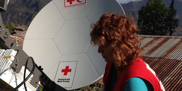 A Red Cross worker in Nepal stands before a VSAT antenna. Photo / American Red Cross