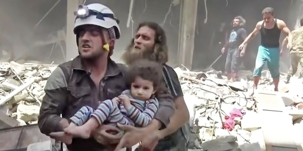 A civil defence worker carries a child wounded by an airstrike in Aleppo on Friday as rescuers comb the ruins. Photo / AP