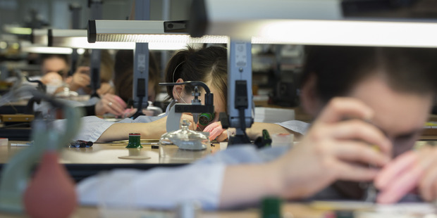 Watchmakers sit at work benches during luxury wristwatch manufacture. Photo / Bloomberg