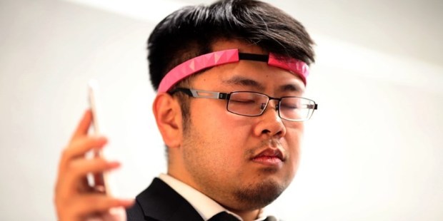 BrainCo CEO Bicheng Han wears the BrainCo Focus 1 to use bio feedback to change the color of a lamp by concentrating. Photo / AFP