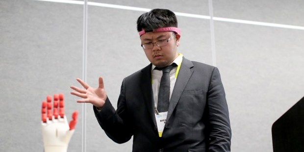Bicheng Han wears the BrainCo Focus 1 to use bio feedback to try concentrate on manipulate a mechanical hand using his brain. Photo / AFP