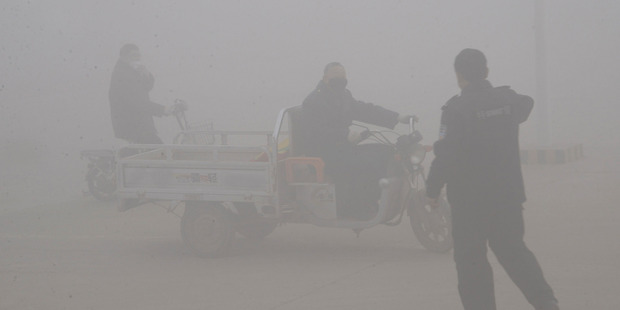 A policeman talks to the driver of a motor-tricycle amid heavy haze in Handan city in northern China's Hebei province. Photo / AP