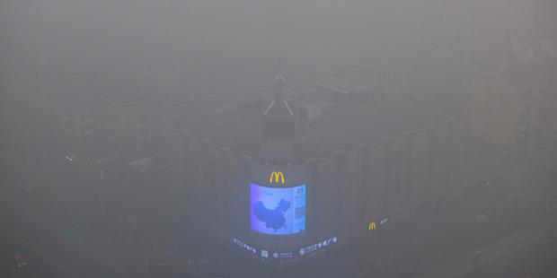 A video display on the side of a building shows a map of China amid heavy pollution and fog in Beijing. Photo / AP
