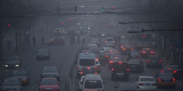 Pedestrians make their way across a busy intersection on a day with severe air pollution in Beijing. Photo / AP