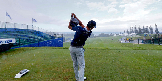 Danny Lee hits from the first tee during a rain shower at the Tournament of Champions golf pro-am. Photo / AP