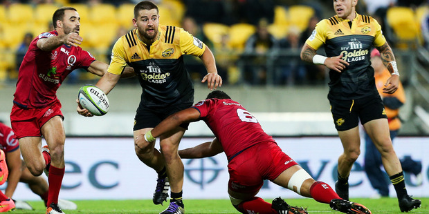 Dane Coles of the Hurricanes looks to pass in the tackle of Hendrik Tui of the Reds. Photo / Getty