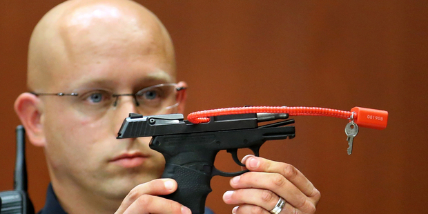 In this June 28, 2013, file photo, Sanford police officer Timothy Smith holds up the gun that was used to kill Trayvon Martin. Photo / AP