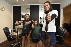 The girls hold their freshly cut ponytails, to be turned into wigs for cancer patients. Photo / George Novak