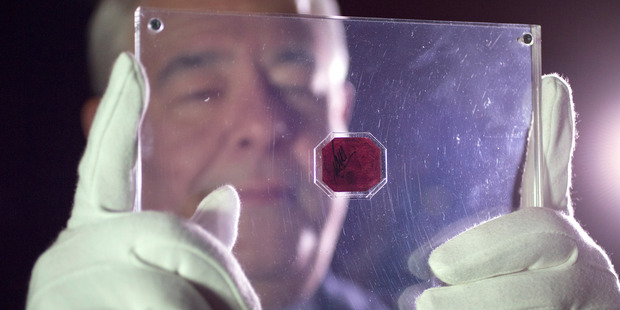 An employee of Sotheby's auction house holds a case containing the sole-surviving 'British Guiana One-Cent Magenta' stamp dating from 1856. The stamp sold for US$8 million. Photo / Getty