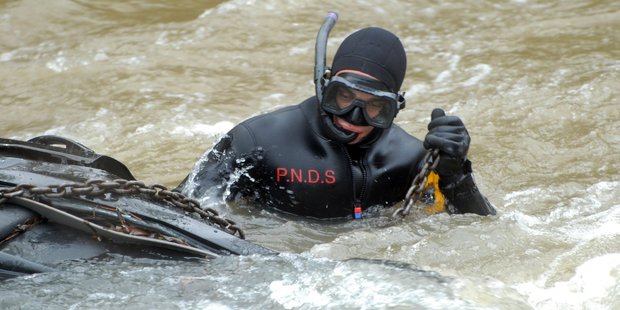 A police diver secures a chain strop to the wreckage of a car that plunged into the Waipoua Riuver near Masterton this morning in a crash that killed a 35-year-old Lower Hutt man.