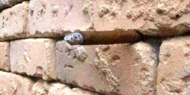 Optical illusion: At first glance it appears we are looking at a normal wall with a simple small rock embedded between two of the red bricks.