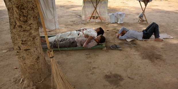Municipal workers and a roadside snack vendor rest under the shade of a tree on a hot afternoon in New Delhi. Much of India is reeling under heat wave. Photo / AP