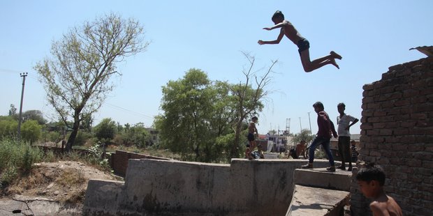 Children jump into a water canal to cool themselves on a hot summer day in Jammu. Photo / AP