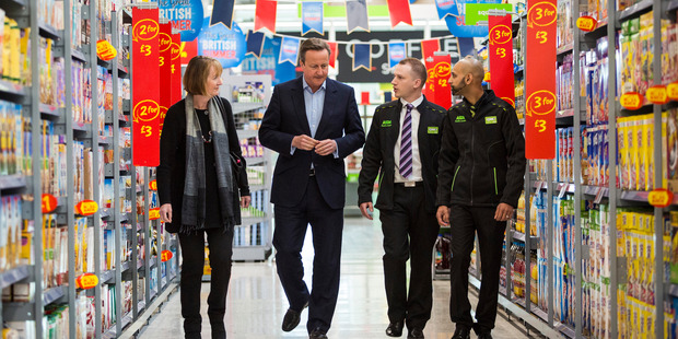 Britain's Prime Minister, David Cameron, 2nd left, speaks to supermarket employees during a visit with former Deputy Labour Party leader, Harriet Harman, left, in Hayes, London. Photo / AP