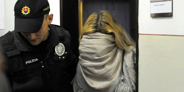 Maria Kukucova, right, hides her face in a scarf as she leaves a court after being taken into custody in Trencin, Slovakia, in 2014. Photo / AP