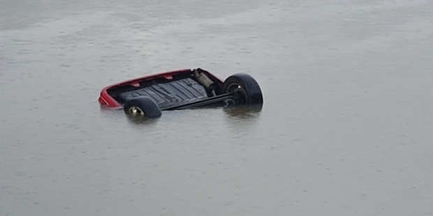 Emergency services on the scene at Henderson after a car plunged into the river with people possibly trapped inside. Photo / Supplied