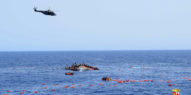 An Italian Navy helicopter flies over the overturned boat. Photo / Marina Militare via AP Photo