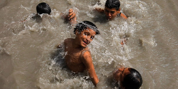 Pakistani boys cool themselves off in a canal during a heat wave in Peshawar, Pakistan. Photo / AP
