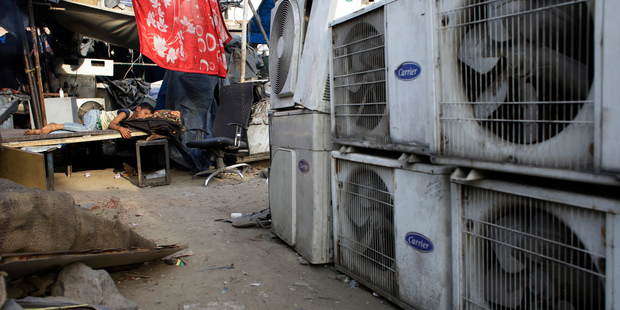An Indian boy sleeps near an air conditioner at a market place in New Delhi, India. Photo / AP