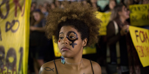 A woman wearing a female gender symbol attends a protest against the gang rape of a 16-year-old girl in Rio de Janeiro, Brazil. Photo / AP