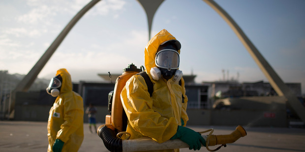 In this Tuesday, Jan. 26, 2016 file photo, a health workers stands in the Sambadrome spraying insecticide to combat the Aedes aegypti mosquito that transmits the Zika virus in Rio de Janeiro, Brazil.