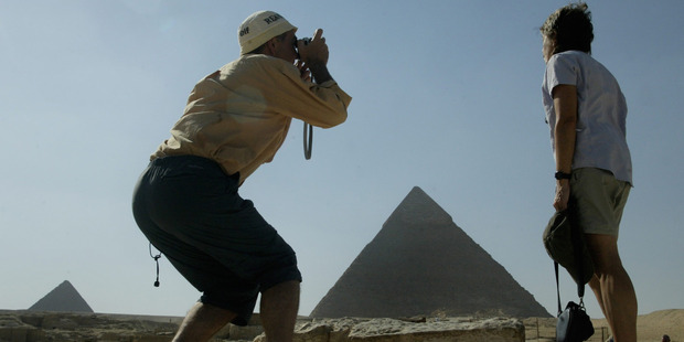 A tourist tries to capture the Sphinx, the Pyramids and his wife in one shot at Giza in Egypt. Photo / Alan Gibson