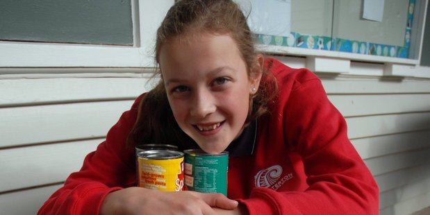 Masterton Intermediate School pupil Millie Matthews, 12, with some of the more than 300 cans she and classmate Leila Ward helped gather for the Masterton Foodbank. PHOTO/NATHAN CROMBIE