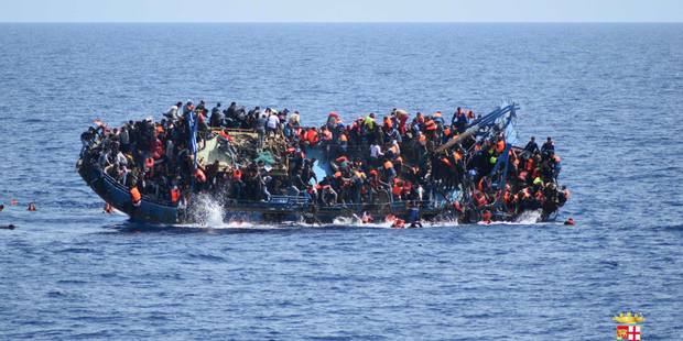People try to jump in the water right before their boat overturns off the Libyan coast in May. Photo / AP