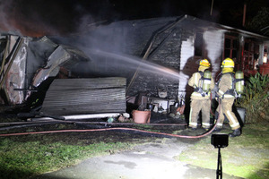 Fire fighters dampen down a house fire on Waiohiki Rd last night.