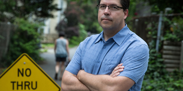 Tim Connor stands by a sign his neighbour purchased to thwart commuters from cutting through their quiet residential street. Photo / Washington Post