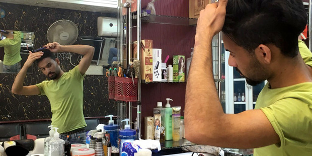 Arkan Ismael combs his hair at the Hajar barbershop where he works in Baghdad. Photo / Washington Post