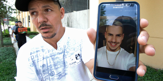 Angel Mendez, standing outside the Orlando Regional Medical Centre, holds up a photo trying to get information about his brother Jean Mendez who was at the Pulse Nightclub. Photo / AP