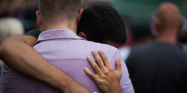 Mourners embrace during a vigil in Orlando for those killed in a mass shooting at the Pulse nightclub. Photo / AP