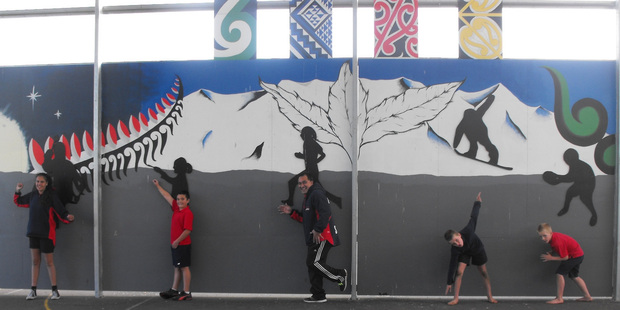 The Raetihi mural on the wall of the covered sports area at the school with Jasmine Follow 12, Caleb Michel-Murphy 12, principal Nuku Wallace, Harry Rowe 9 and Sam Rowe 7.