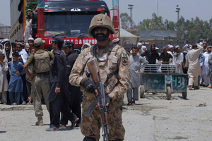 Pakistani troops stand guard while Afghans wait to cross border through the Torkham border crossing in Torkham, Pakistan. Photo / AP