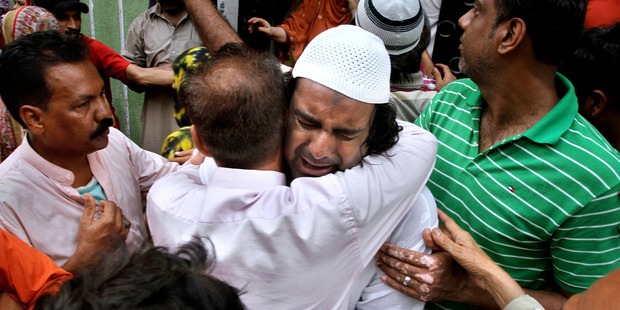 People comfort the brother, centre, of Sufi singer Amjad Sabri, who was killed by unknown attackers, outside his residence in Karachi, Pakistan. Photo / AP