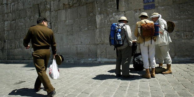 A Syrian police officer looks at German tourists as he walks past at the walls of the Old Town in Damascus in 2005. Photo / Getty Images