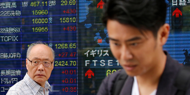 People walk past an electronic stock indicator of a securities firm in Tokyo. Photo / AP