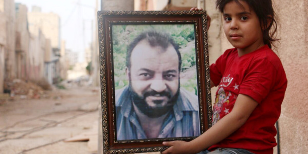 Maram Lahham in Darayya, Syria, holds a photo of her father, Bashar, who was killed two years ago by a government sniper in the besieged town. Photo / Washington Post