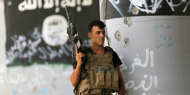 A member of Iraqi counterterrorism forces stands guard near Islamic State militant graffiti in Fallujah. Photo / AP